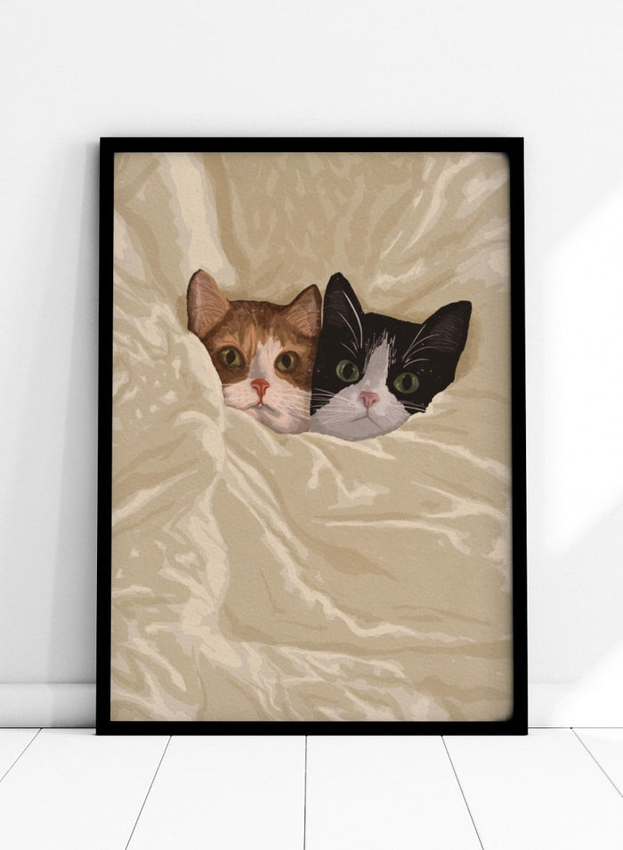 A stylized illustration of two cats peeking out from under a rumpled cream-colored blanket. The cat on the left is orange and white, and the cat on the right is black and white.  Cozy Cats Peeking Out by Lisa Solomoniuk premium framed fine art print featuring two cats tucked into soft cream bedding with wide-eyed expressions.