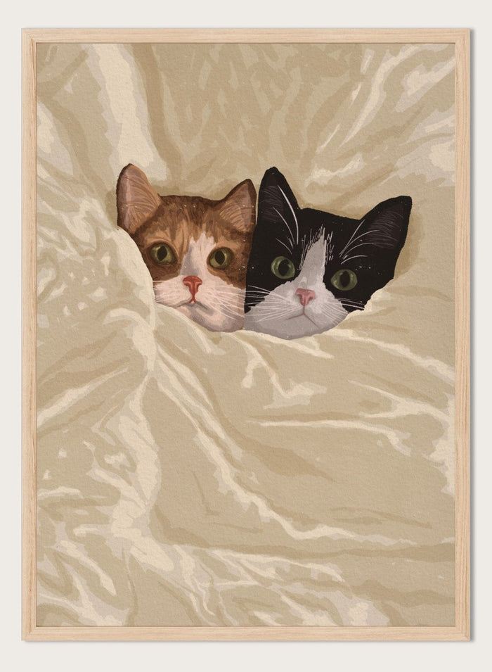 A stylized illustration of two cats peeking out from under a rumpled cream-colored blanket. The cat on the left is orange and white, and the cat on the right is black and white.  Cozy Cats Peeking Out by Lisa Solomoniuk premium framed fine art print featuring two cats tucked into soft cream bedding with wide-eyed expressions.