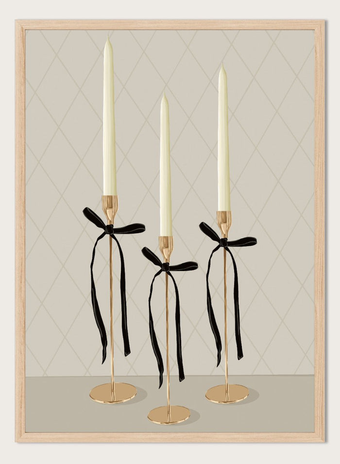 Three gold taper candle holders with cream candles and black ribbon bows, arranged on a light gray surface against a beige diamond-patterned background. Elegant Gold Taper Candles by Lisa Solomoniuk premium framed fine art print featuring gold candlesticks, cream tapers, and long black ribbons.
