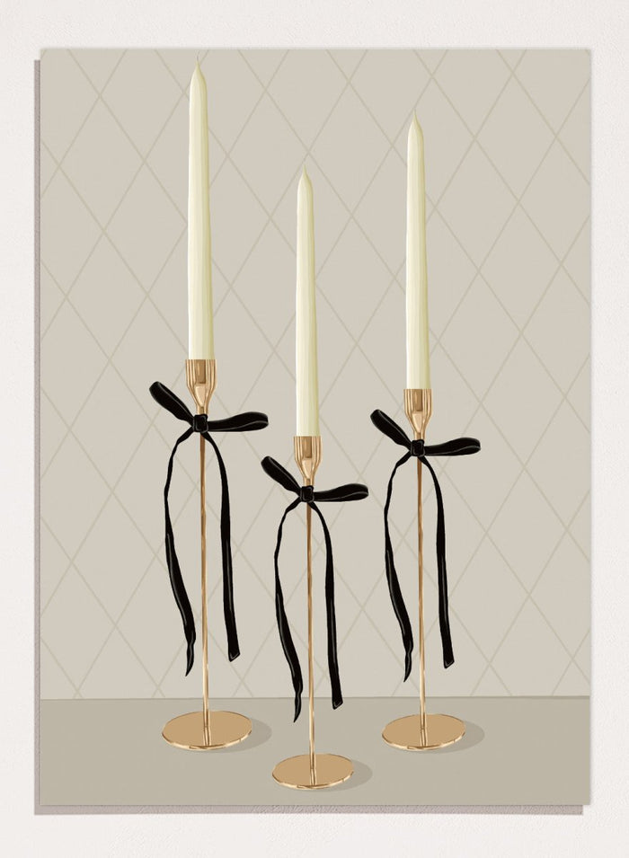 Three gold taper candle holders with cream candles and black ribbon bows, arranged on a light gray surface against a beige diamond-patterned background. Elegant Gold Taper Candles by Lisa Solomoniuk premium framed fine art print featuring gold candlesticks, cream tapers, and long black ribbons.