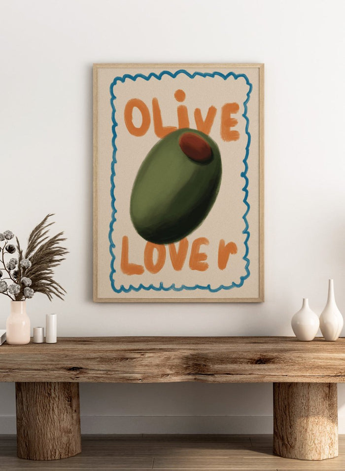 An art print featuring a stylized illustration of an olive with the words 'OLIVE' at the top and 'LOVE' at the bottom, framed by a blue scalloped border on a cream background. Green Olive Lover by Lisa Solomoniuk premium framed fine art print featuring an oversized green olive, orange lettering, and a playful blue border.