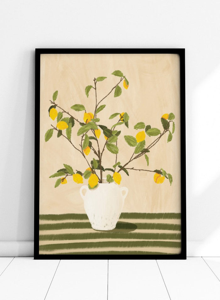 A framed still life artwork showing yellow lemons on leafy branches arranged in a white vase, set against a warm beige background with green horizontal stripes at the bottom. Lemon Tree Still Life by Lisa Solomoniuk premium framed fine art print featuring bright yellow lemons in a white vase on a striped green table.