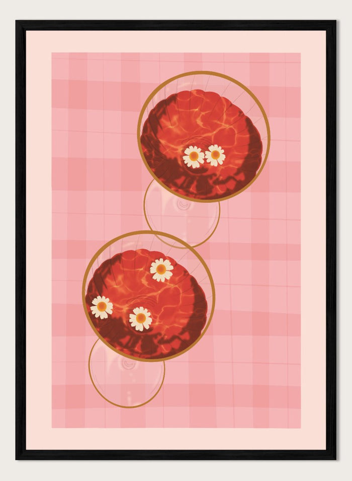 A stylized art print featuring two overlapping pink and red plaid glasses with white daisy flowers, framed by a black border on a light pink background. Pink Drinks With Daisies by Lisa Solomoniuk premium framed fine art print featuring red coupe glasses, floating daisies, and pink gingham.