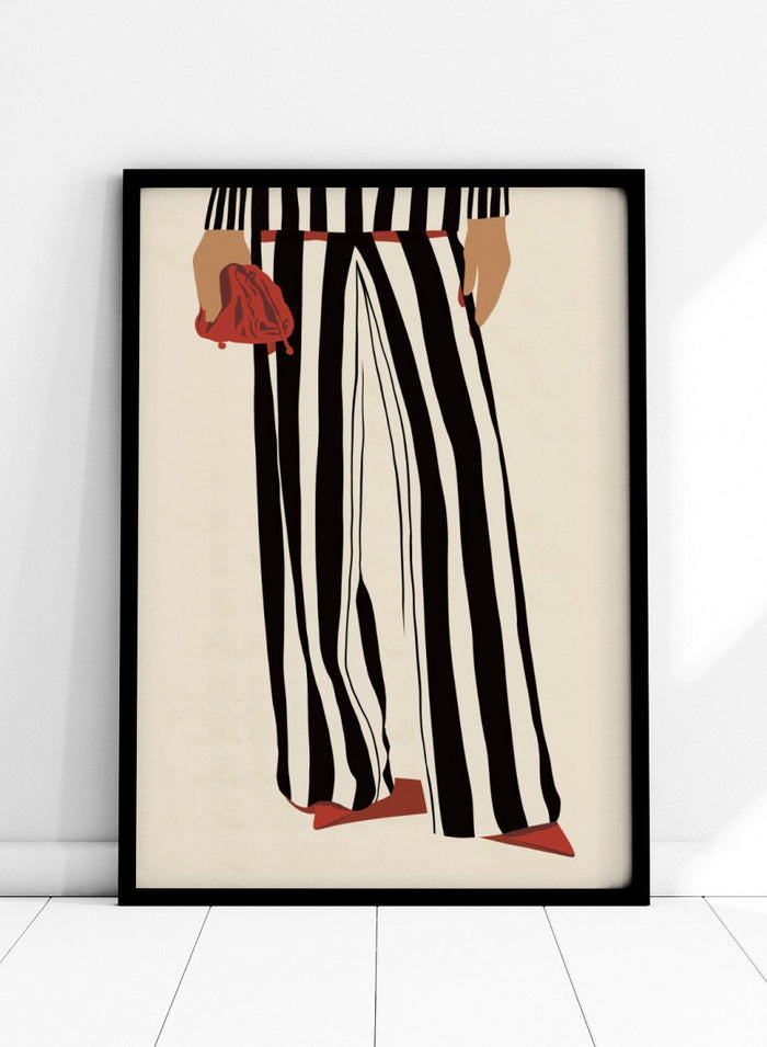 Fashion illustration of a person from the waist down wearing black and white vertically striped wide-leg trousers, with a red belt, red pointed shoes, and holding a red clutch against a cream background. Red Heels and Stripes by Lisa Solomoniuk premium framed fine art print featuring bold black-and-white stripes, pointed red heels, and a matching bag.