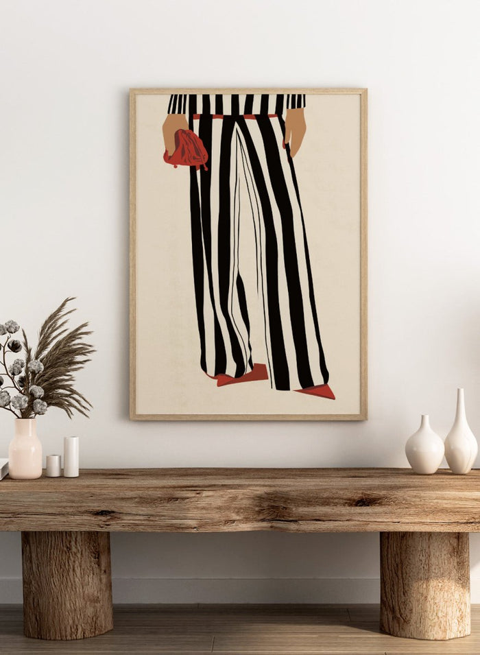 Fashion illustration of a person from the waist down wearing black and white vertically striped wide-leg trousers, with a red belt, red pointed shoes, and holding a red clutch against a cream background. Red Heels and Stripes by Lisa Solomoniuk premium framed fine art print featuring bold black-and-white stripes, pointed red heels, and a matching bag.