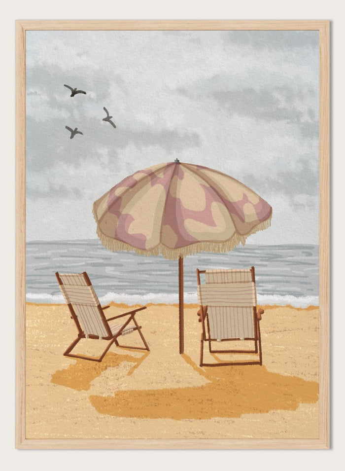 A beach scene artwork showing two wooden deck chairs under a beige and dusty pink patterned umbrella on a sandy shore, with the ocean and cloudy sky behind them. Two birds are visible in the sky. Seaside Umbrella Chairs by Lisa Solomoniuk premium framed fine art print featuring striped beach chairs beneath a fringed umbrella by the sea.