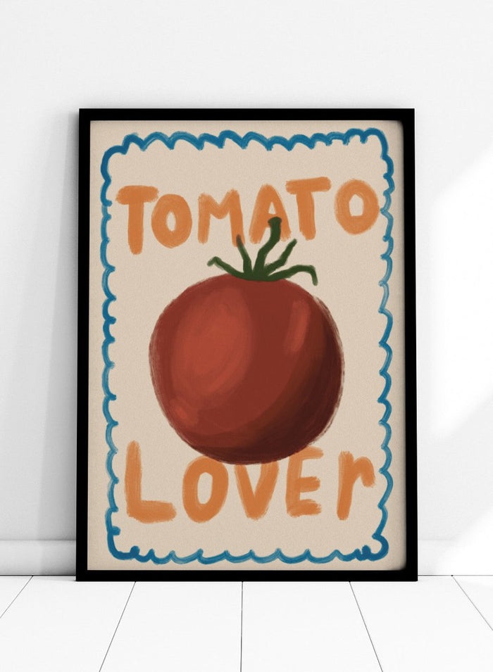 An art print featuring a painted red tomato with a green stem, surrounded by a scalloped blue border on a cream background. The words 'TOMATO' at the top and 'LOVER' at the bottom are written in orange hand-drawn lettering. Tomato Lover by Lisa Solomoniuk premium framed fine art print featuring an oversized tomato, playful hand-painted lettering, and a wavy border.