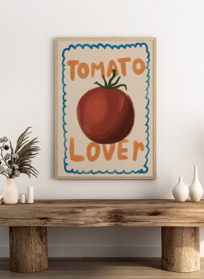 An art print featuring a painted red tomato with a green stem, surrounded by a scalloped blue border on a cream background. The words 'TOMATO' at the top and 'LOVER' at the bottom are written in orange hand-drawn lettering. Tomato Lover by Lisa Solomoniuk premium framed fine art print featuring an oversized tomato, playful hand-painted lettering, and a wavy border.