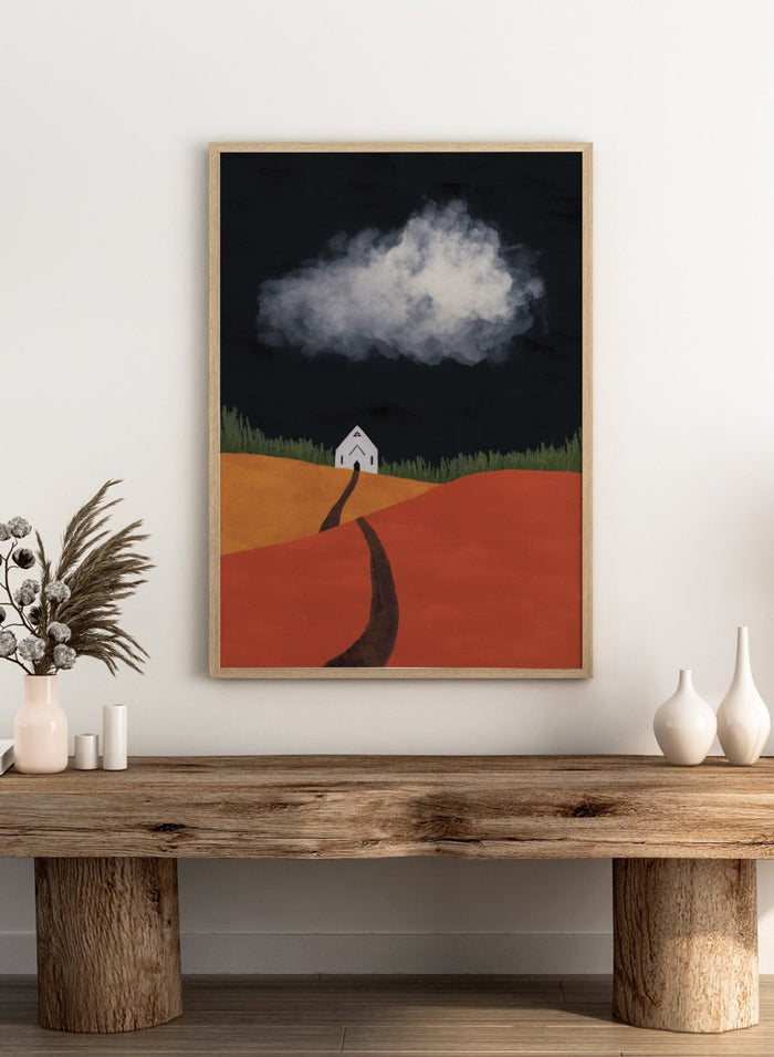 A stylized landscape artwork showing a white house on a hill, a dark winding path, orange and yellow fields, green grass, and a large white cloud against a very dark sky. Winding Path Church by Lisa Solomoniuk premium framed fine art print featuring a small white church beneath a dramatic cloud over red and ochre hills.