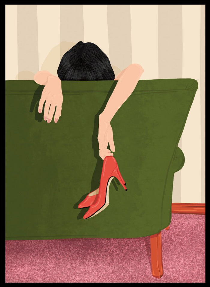 A stylized illustration of a person sitting on a green sofa, holding a pair of red high-heeled shoes. The person has dark hair and pale skin, with striped beige walls and a pink carpet in the background. Woman Resting Red Heels by Lisa Solomoniuk premium framed fine art print featuring a woman draped over a green chair holding bright red heels.