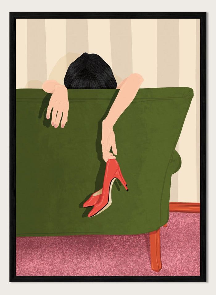 A stylized illustration of a person sitting on a green sofa, holding a pair of red high-heeled shoes. The person has dark hair and pale skin, with striped beige walls and a pink carpet in the background. Woman Resting Red Heels by Lisa Solomoniuk premium framed fine art print featuring a woman draped over a green chair holding bright red heels.