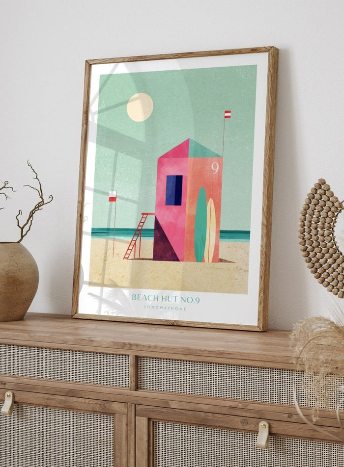 Colorful beach hut illustration with a minimalistic design on a light green background. Beach Hut Number Nine by Longwayhome is a retro inspired coastal art print featuring a colorful beach hut, surfboards, and minimalist seaside design.