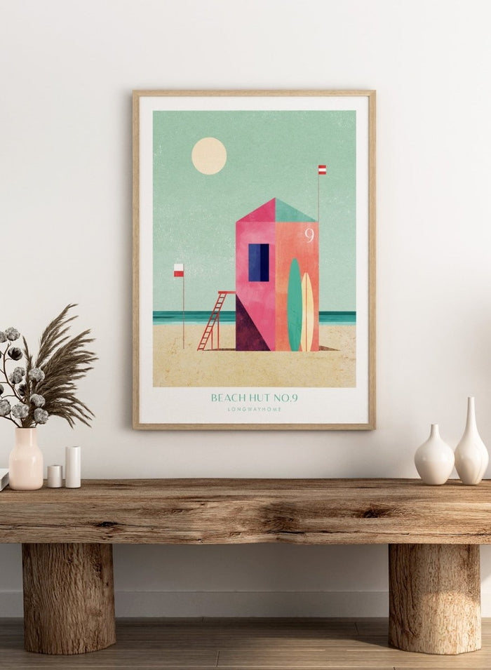 Colorful beach hut illustration with a minimalistic design on a light green background. Beach Hut Number Nine by Longwayhome is a retro inspired coastal art print featuring a colorful beach hut, surfboards, and minimalist seaside design.