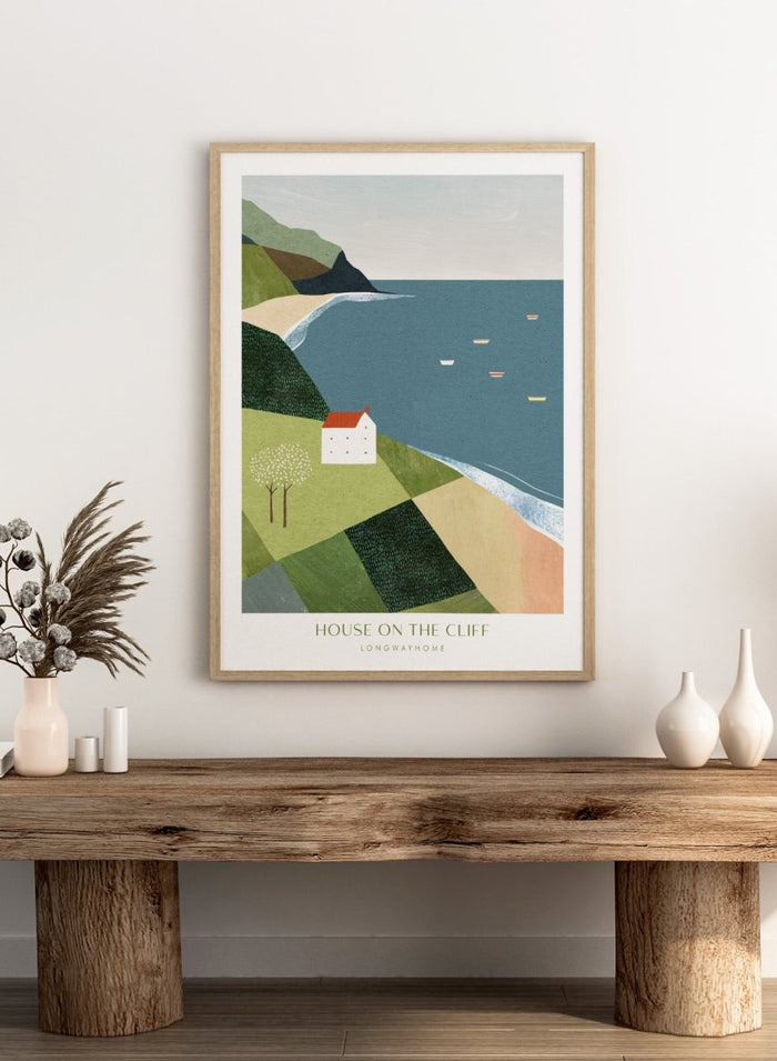 Illustration of a house on a cliff overlooking a coastal scene with boats. House on the Cliff by Longwayhome is a minimalist coastal landscape art print featuring ocean views, cliffside scenery, and modern travel inspired wall art.