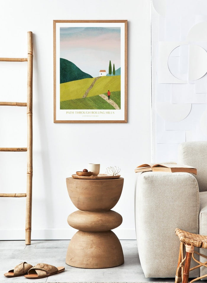 Illustration of a person walking along a path through rolling hills with a house and trees in the background. Path Through Rolling Hills by Longwayhome is a minimalist landscape art print featuring rolling green hills, countryside scenery, and modern travel inspired wall art.