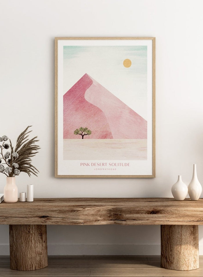 Artistic depiction of a pink desert with a solitary tree and a yellow sun. Pink Desert Solitude by Longwayhome is a minimalist desert art print featuring soft pink dunes, abstract landscape scenery, and calming modern design.