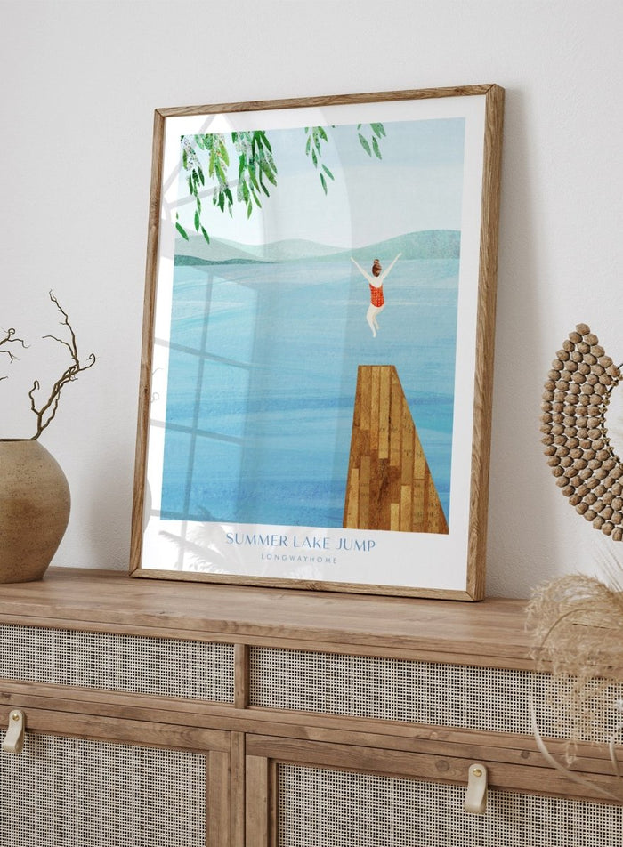 Illustration of a person jumping into a lake from a dock with mountains in the background. Summer Lake Jump by Longwayhome is a minimalist summer lake art print featuring a dock jump scene, calm blue water, and modern travel inspired design.