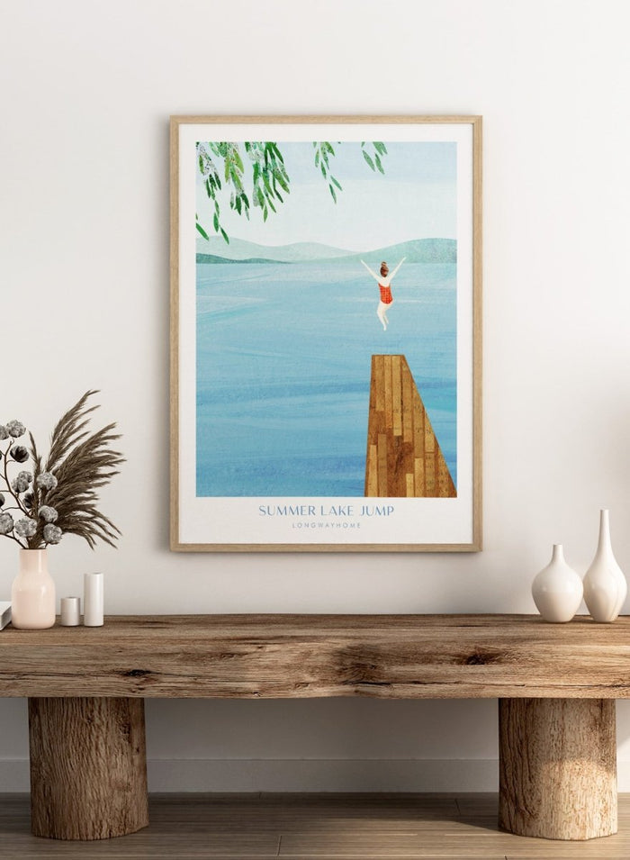 Illustration of a person jumping into a lake from a dock with mountains in the background. Summer Lake Jump by Longwayhome is a minimalist summer lake art print featuring a dock jump scene, calm blue water, and modern travel inspired design.