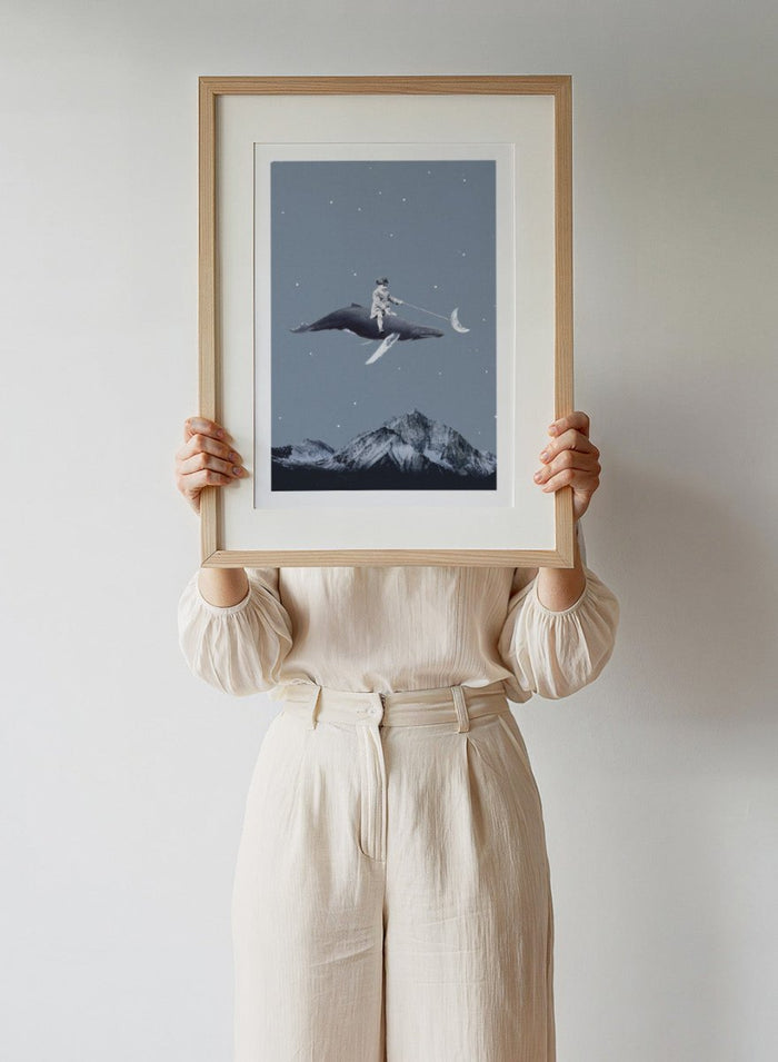 Aim for the Moon by Maarten Léon is a surreal collage art print featuring a boy riding a whale in a starry sky with mountains and moon imagery.