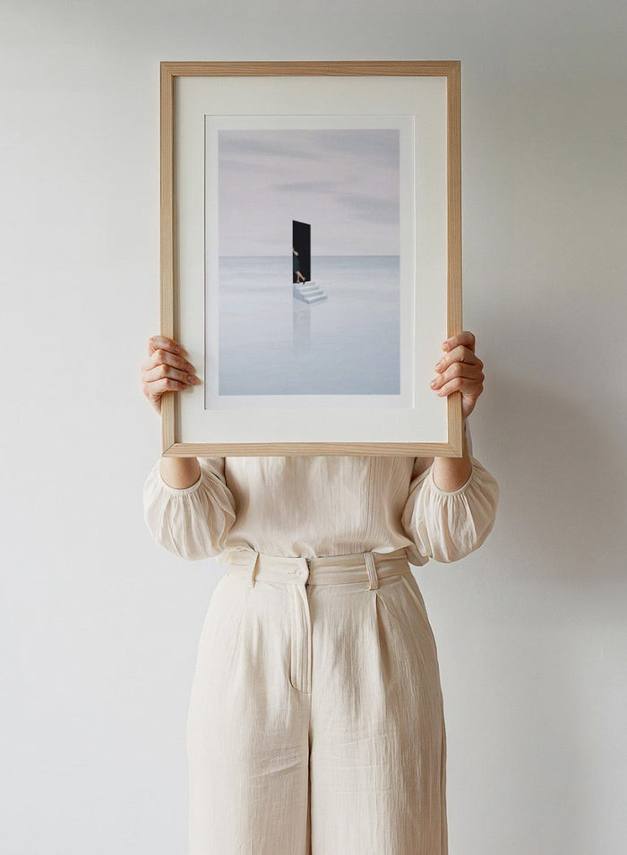 Curiosity by Maarten Léon is a minimalist collage art print showing a figure peering into a blue opening. Premium fine art print with real wood framing.