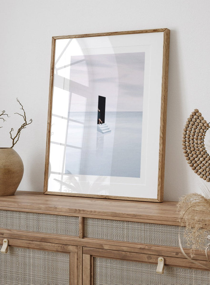Curiosity by Maarten Léon is a minimalist collage art print showing a figure peering into a blue opening. Premium fine art print with real wood framing.