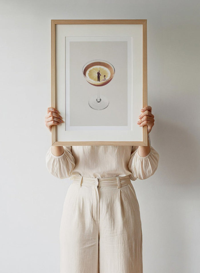 My Drink Needs a Drink by Maarten Léon is a minimalist collage art print featuring a lemon cocktail scene with vintage figures and playful surreal detail.