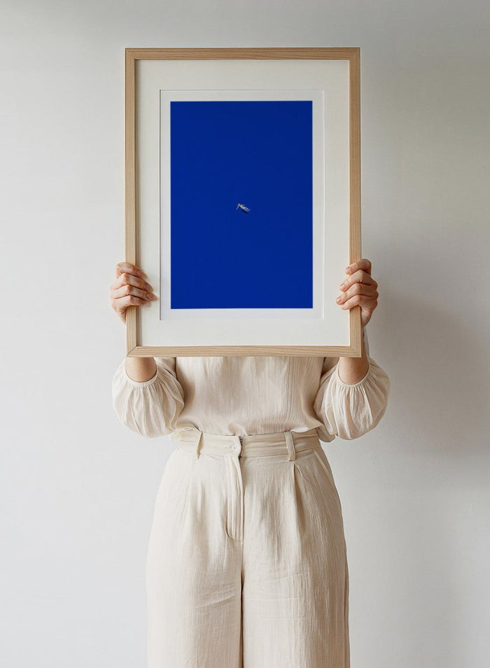 No Stress by Maarten Léon is a minimalist collage art print featuring a floating figure in a bold blue space. Premium fine art print with real wood framing.