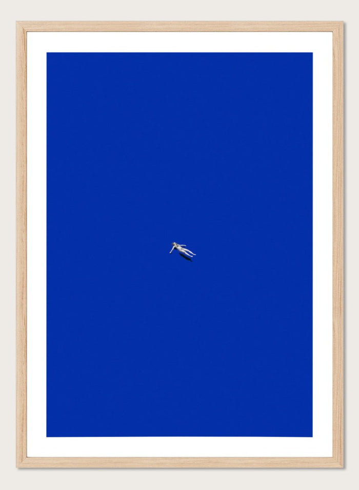 No Stress by Maarten Léon is a minimalist collage art print featuring a floating figure in a bold blue space. Premium fine art print with real wood framing.