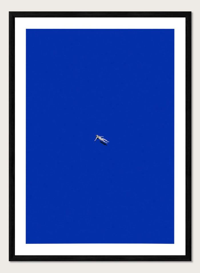 No Stress by Maarten Léon is a minimalist collage art print featuring a floating figure in a bold blue space. Premium fine art print with real wood framing.