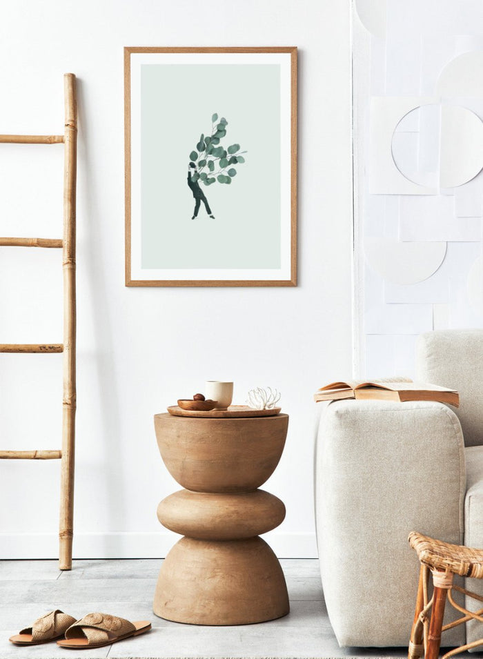 The Extravert by Maarten Léon collage art print showing a figure holding oversized eucalyptus branches. Premium fine art print with real wood framing.