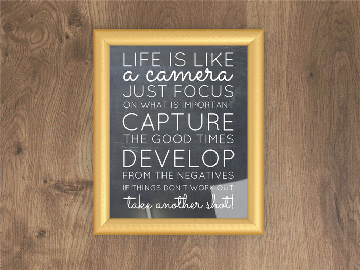 Gold picture and poster frames featuring inspirational quote, displayed on wooden background.