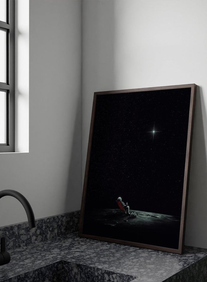 Person sitting on a chair under a starry sky. Astronaut Star Gazer by Nicebleed is a surreal space art print featuring a lone astronaut under a star-filled sky, modern aesthetic wall poster.