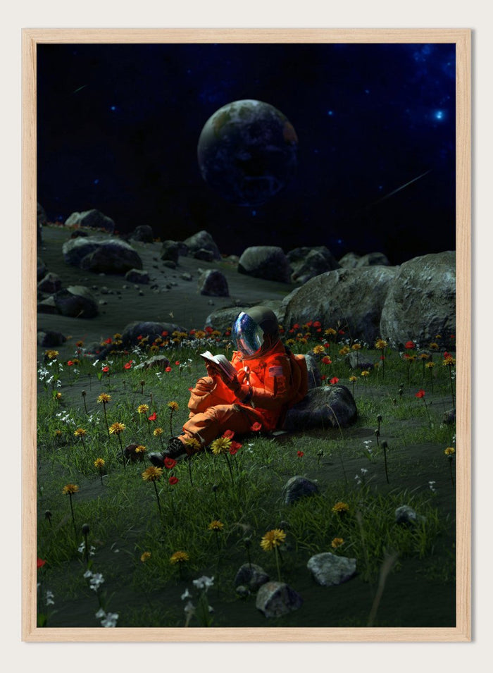 Person in orange spacesuit sitting on the moon reading a book with a large moon and stars in the background. Astronaut’s Alien Garden by Nicebleed is a surreal space art print featuring an astronaut reading in a floral alien landscape, modern aesthetic wall poster.