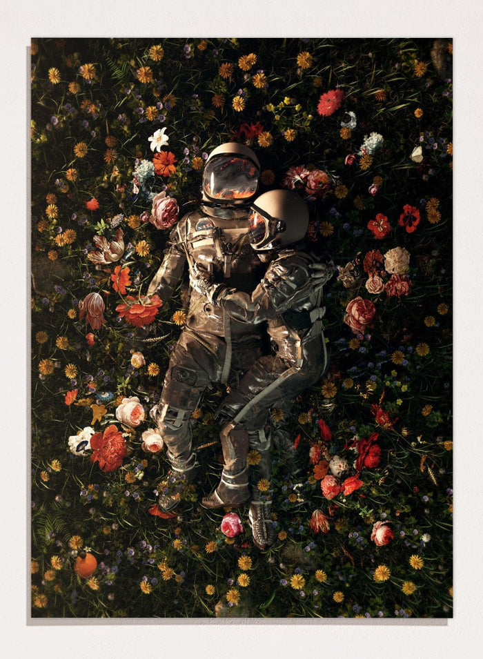 Astronaut lying on a bed of flowers with a dark background. Cosmic Couple Bloom by Nicebleed is a surreal astronaut floral art print featuring two astronauts in a field of flowers, modern aesthetic wall poster.
