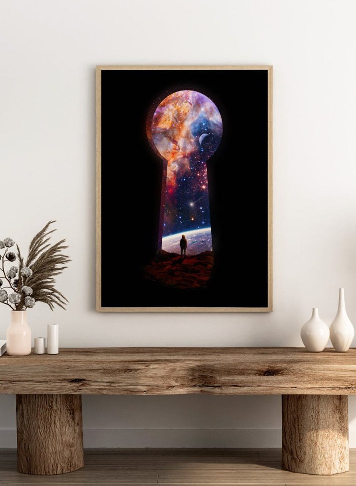 Keyhole-shaped portal to space with a silhouette of a person looking into it. The Cosmic Keyhole by Nicebleed is a surreal space art print featuring an astronaut looking through a cosmic keyhole, modern aesthetic wall poster.