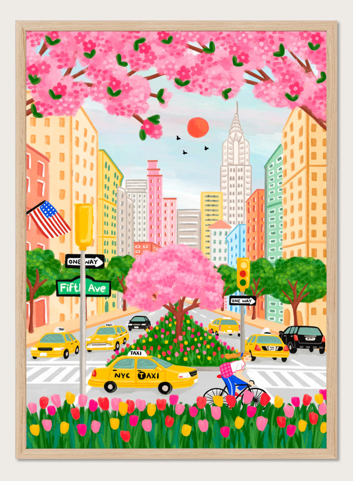 A colorful illustrated city street scene with pink cherry blossoms overhead, yellow NYC taxis, tall buildings, a bicycle with a pink basket, flowers in the foreground, and street signs including Fifti Ave. Shop NYC Cherry Blossoms by Nidhi Kachhadiya, a colorful New York City wall art print with Fifth Avenue, yellow taxis, pink blossoms, and spring city charm.