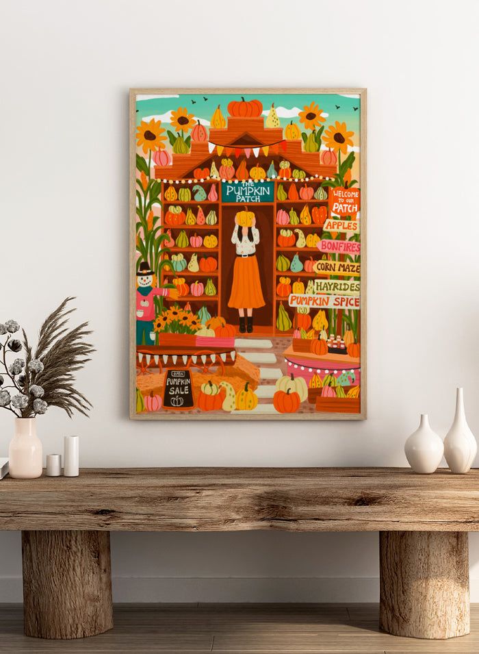A colorful autumn-themed illustration of a woman standing in the doorway of 'The Pumpkin Patch' market stall, surrounded by shelves of pumpkins and gourds, sunflowers, corn maze signs, and a pumpkin sale chalkboard. Shop Vibrant Pumpkin Patch by Nidhi Kachhadiya, a colorful fall art print featuring pumpkins, gourds, sunflowers, and playful autumn market details.