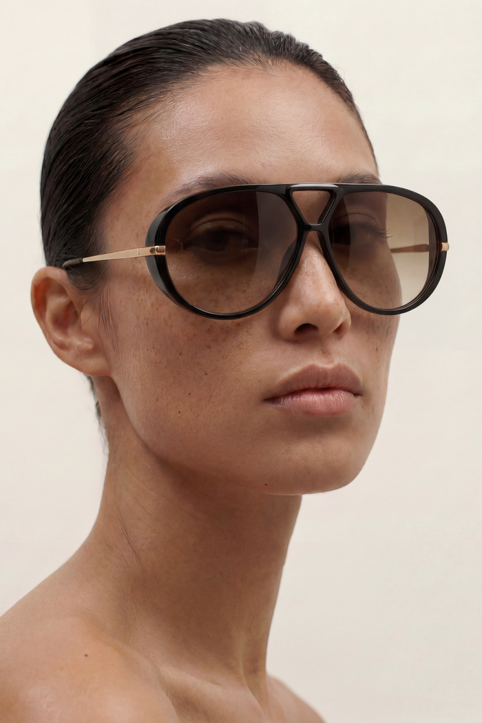Woman wearing large aviator sunglasses on a plain background