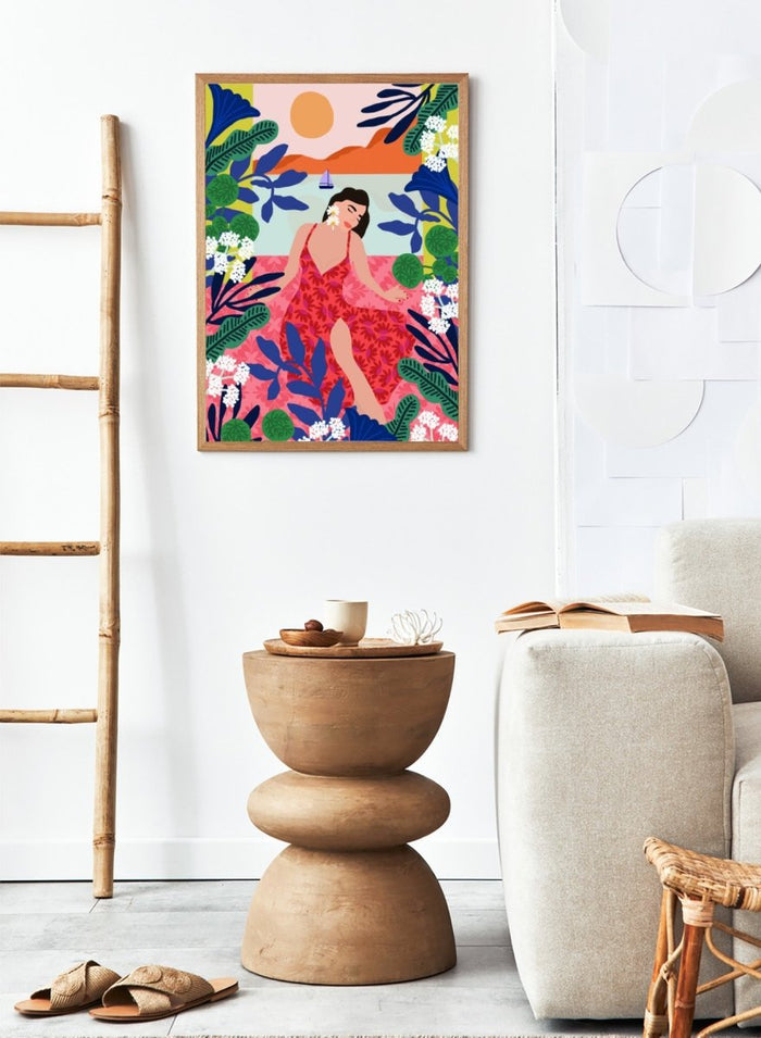 Woman in a red dress surrounded by tropical plants and flowers with a colorful sky. Floral Sunset Girl by Rafaela Mascaro is a vibrant tropical art print featuring bold florals, lush botanicals, coastal views, and colorful contemporary illustration.