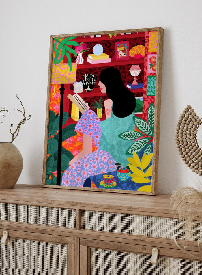 Illustration of a women sitting together with a colorful, patterned background. Girl Reading Her Favorite Book by Rafaela Mascaro fine art print poster featuring woman reading, red bookshelf, bold patterns, plants, modern contemporary wall art.