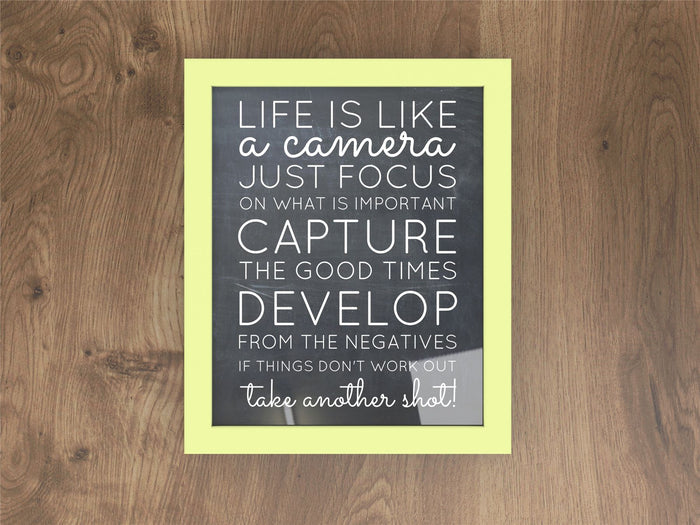 Green picture frame featuring an inspirational quote about life and photography on a wooden background