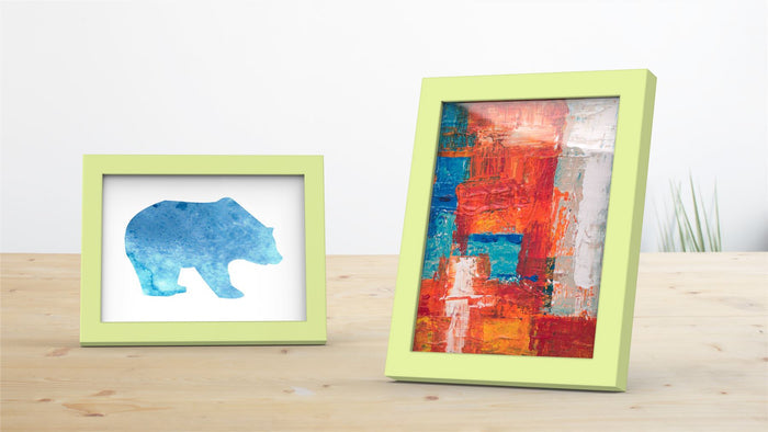 Two green picture frames displaying a blue bear silhouette and a colorful abstract painting.