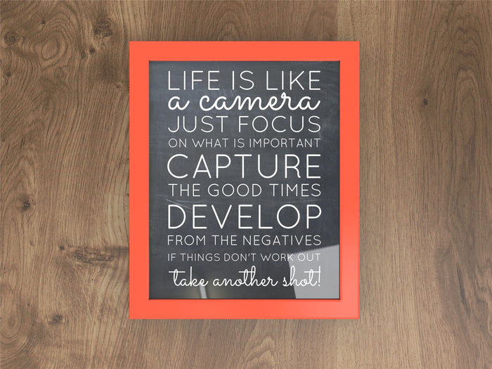 Red picture and poster frame with inspirational quote about photography on a wooden background.