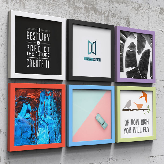 Colorful display of various white picture and poster frames featuring prints and artwork on a concrete wall.