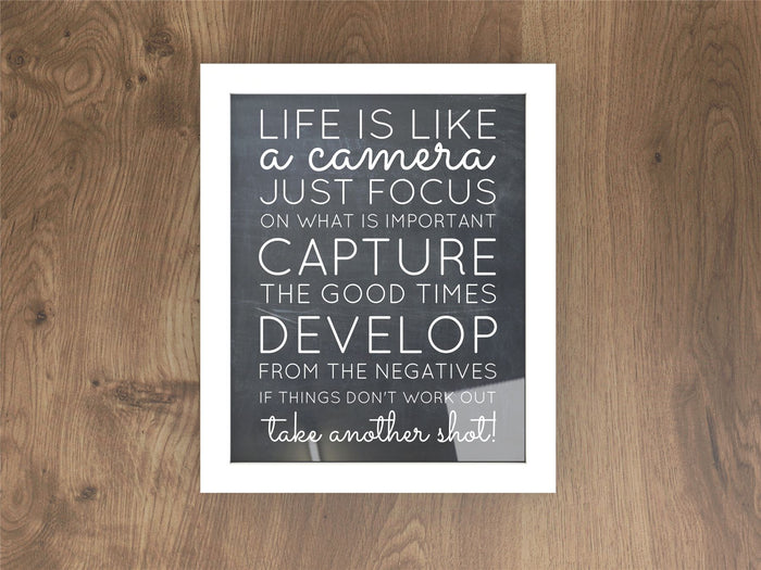 Inspiration quote framed in a white picture and poster frame on wood background.