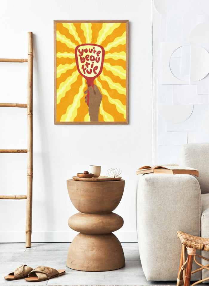 Hand holding a sign with 'You're beautiful' on an orange and yellow background. Beautiful by Raissa Oltmanns is a modern motivational art print featuring a hand mirror illustration, bold lettering, and bright statement wall poster style.