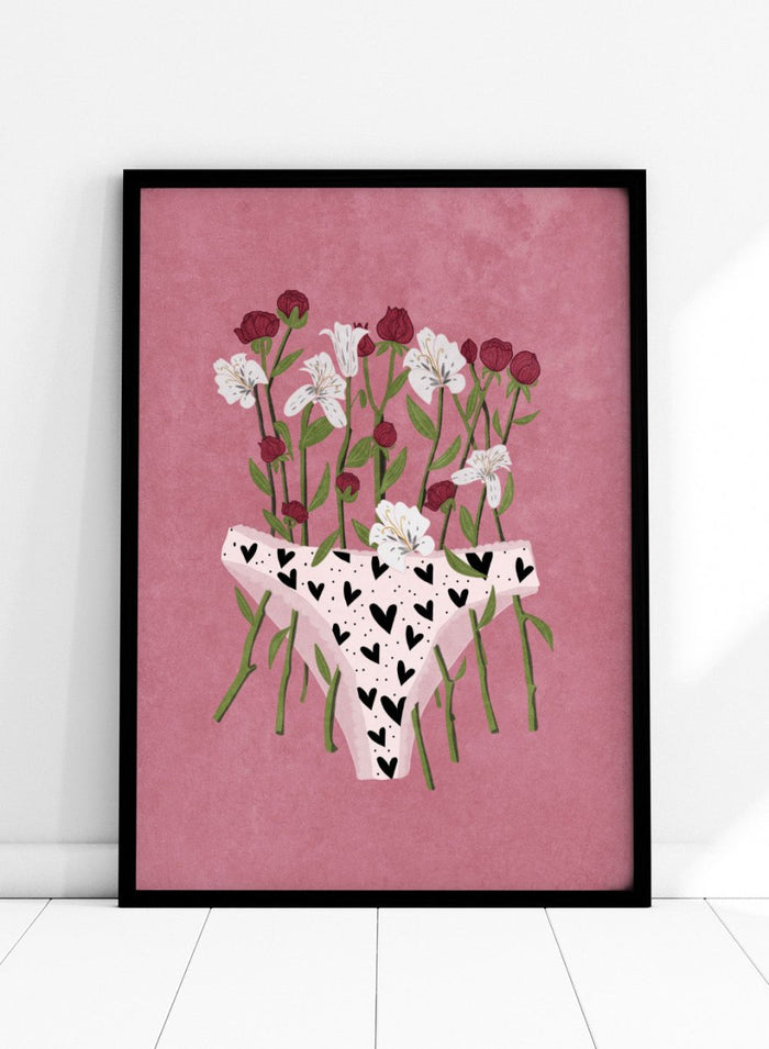 White underwear with black heart patterns surrounded by flowers on a pink background. Blooming Slip by Raissa Oltmanns features a feminist illustration of flowers growing from heart-patterned underwear on a pink background. Bold floral art print with strong feminine symbolism.