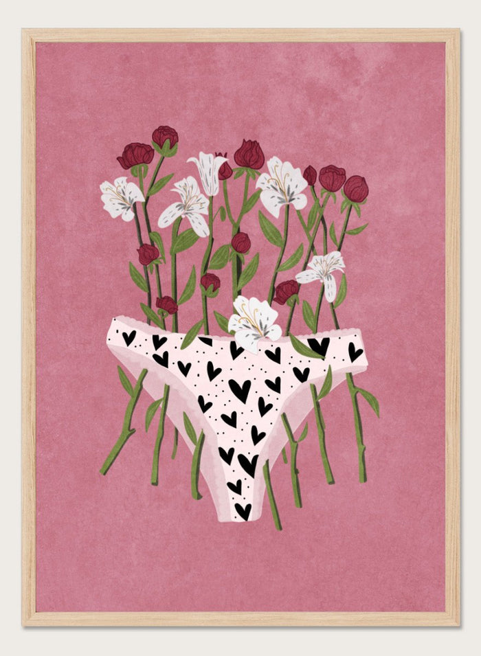 White underwear with black heart patterns surrounded by flowers on a pink background. Blooming Slip by Raissa Oltmanns features a feminist illustration of flowers growing from heart-patterned underwear on a pink background. Bold floral art print with strong feminine symbolism.