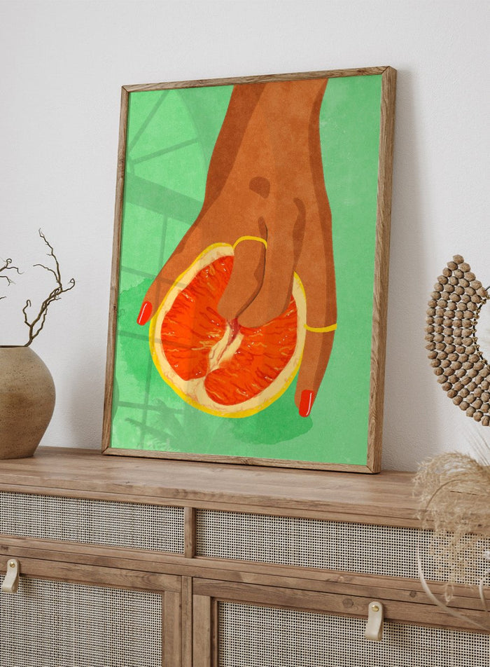 Illustration of a hand holding a sliced orange against a green background. Fruit Lover wall art print by Raissa Oltmanns blends playful citrus and intimate symbolism in a contemporary modern aesthetic poster.