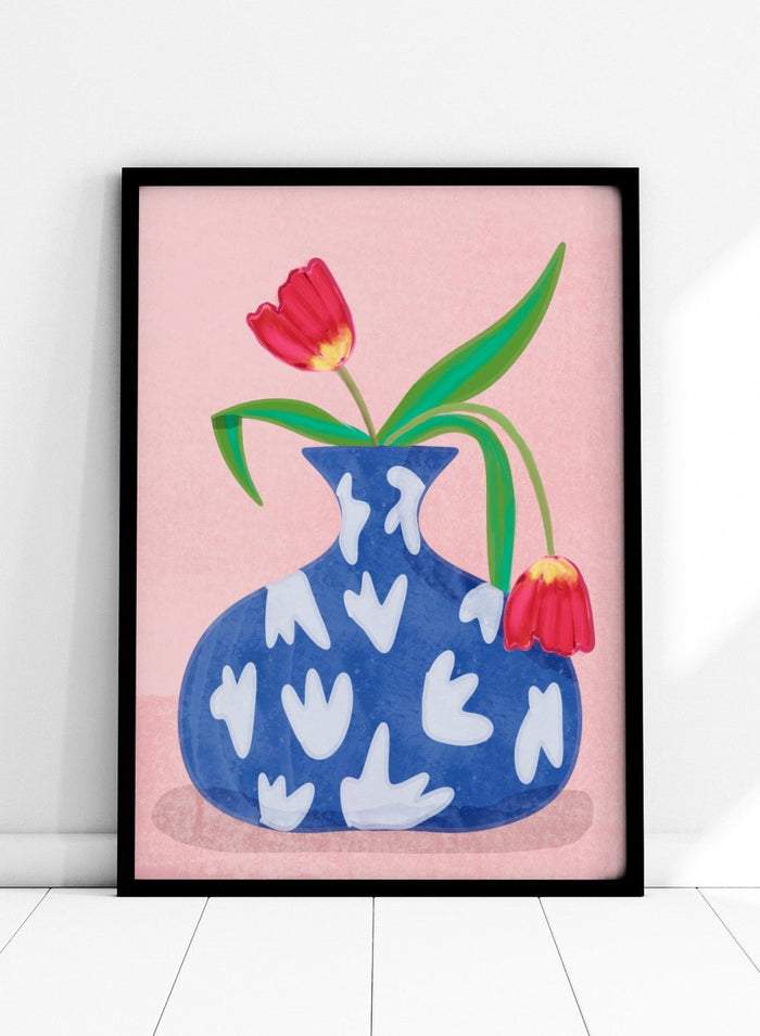 Blue vase with white abstract patterns and red tulips on a pink background. Tulip in Vase by Raissa Oltmanns fine art print featuring bold red tulip, blue patterned vase, modern contemporary floral wall decor poster.